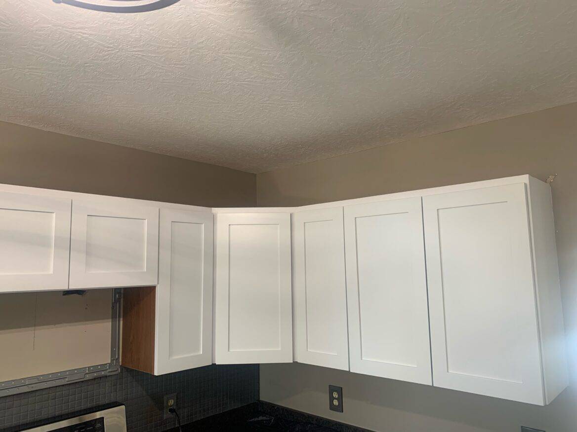 White kitchen cabinets with brand new doors providing a fresh, clean, and modern look to the kitchen.
